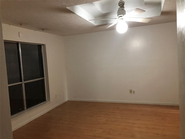 unfurnished room featuring a textured ceiling, ceiling fan, baseboards, and light wood-style floors