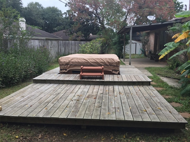 wooden terrace featuring a covered hot tub, a fenced backyard, an outdoor structure, and a shed