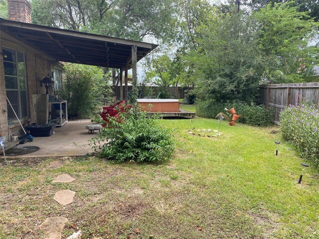 view of yard with a patio area, fence, and a hot tub