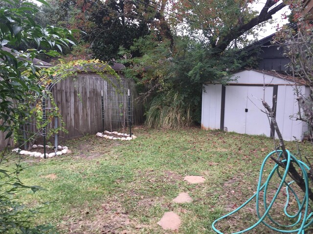 view of yard featuring fence, a storage unit, and an outbuilding