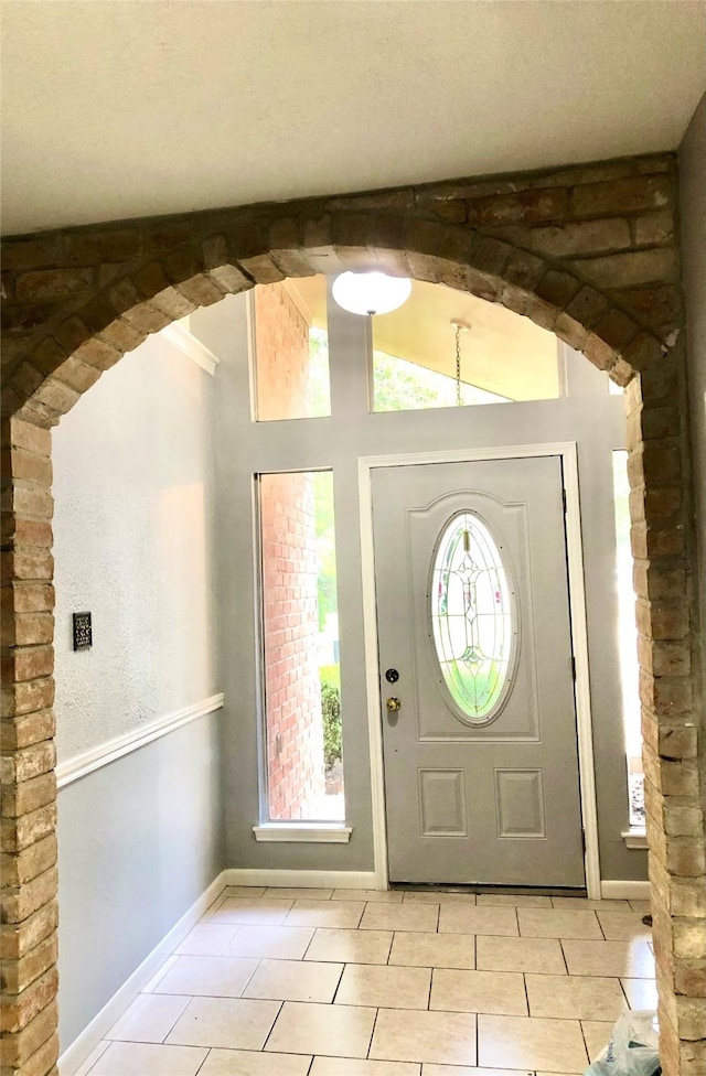 entrance foyer featuring light tile patterned floors and lofted ceiling with beams