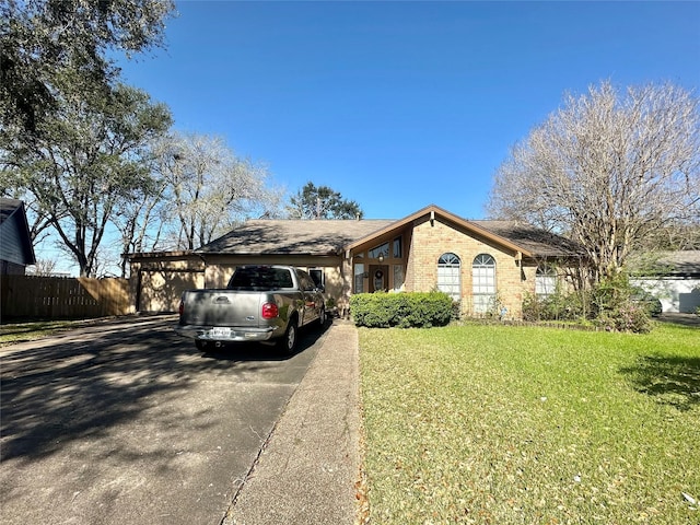 view of front of property featuring aphalt driveway, a front lawn, fence, and brick siding