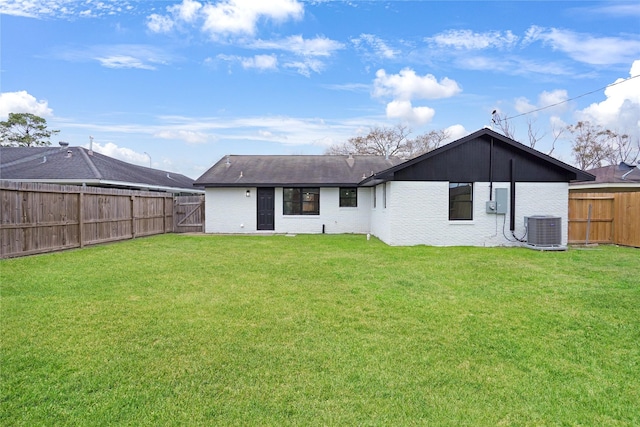 rear view of house featuring central AC and a lawn