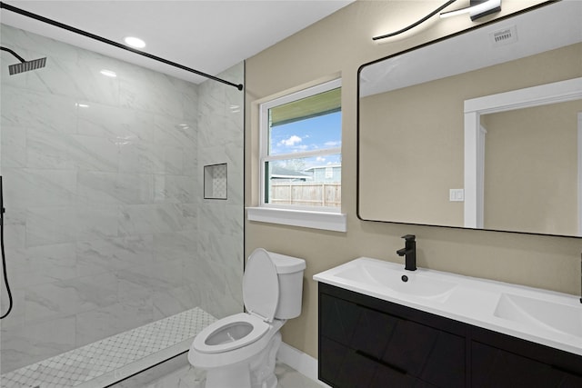 bathroom with vanity, toilet, and a tile shower