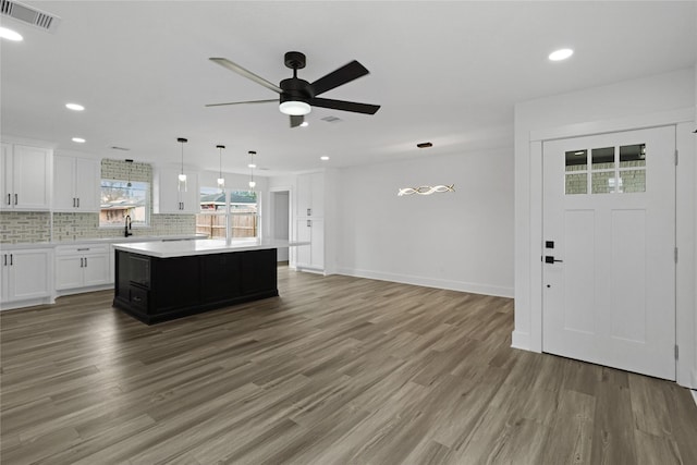 kitchen featuring pendant lighting, hardwood / wood-style floors, a center island, tasteful backsplash, and white cabinets