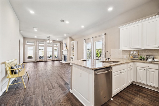 kitchen with dark wood-type flooring, a fireplace, a sink, open floor plan, and stainless steel dishwasher