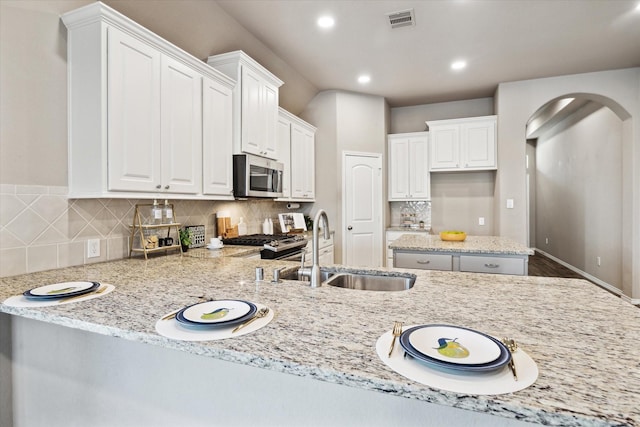 kitchen with visible vents, stainless steel microwave, stove, white cabinetry, and a sink