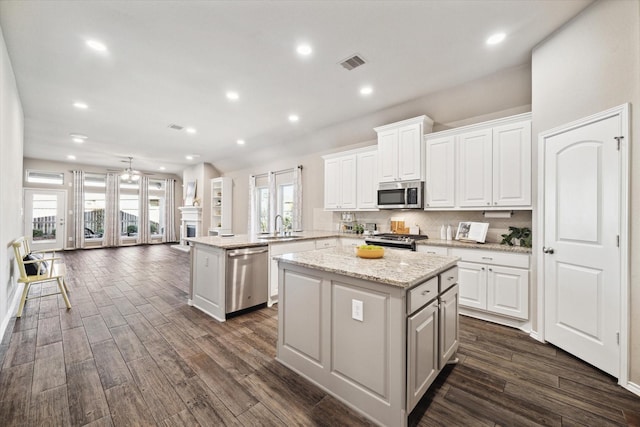 kitchen with a center island, visible vents, appliances with stainless steel finishes, white cabinetry, and a sink