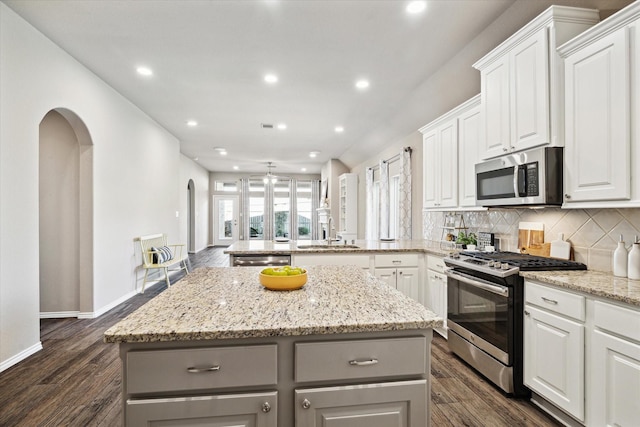 kitchen with decorative backsplash, a center island, stainless steel appliances, gray cabinetry, and a sink