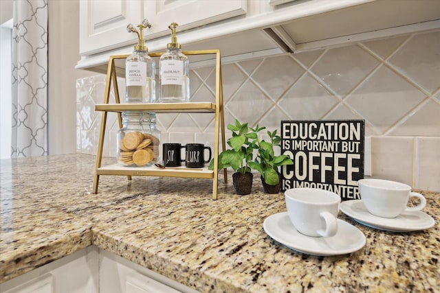 details featuring tasteful backsplash, white cabinetry, and light stone counters