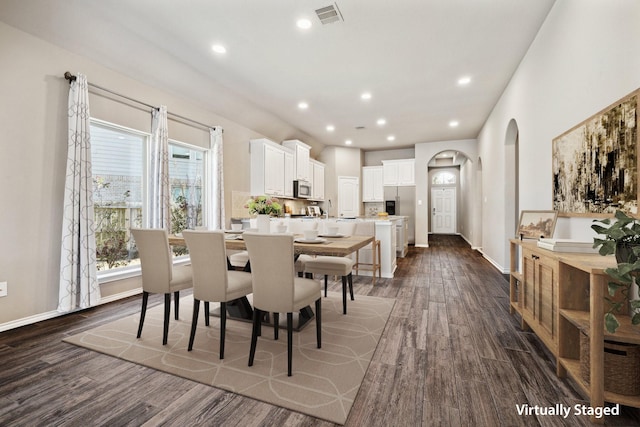 dining space with baseboards, visible vents, arched walkways, dark wood-style flooring, and recessed lighting