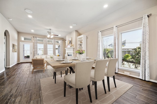 dining room with arched walkways, dark wood finished floors, baseboards, and recessed lighting