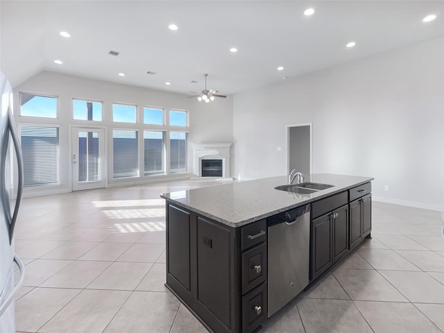 kitchen featuring sink, light tile patterned floors, appliances with stainless steel finishes, a kitchen island with sink, and light stone countertops