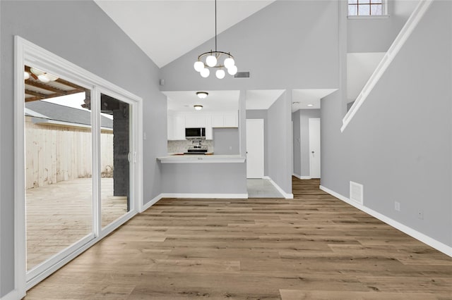 interior space featuring a notable chandelier, high vaulted ceiling, and light hardwood / wood-style flooring