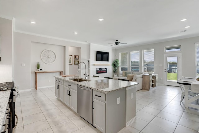 kitchen with appliances with stainless steel finishes, white cabinetry, an island with sink, sink, and light stone counters