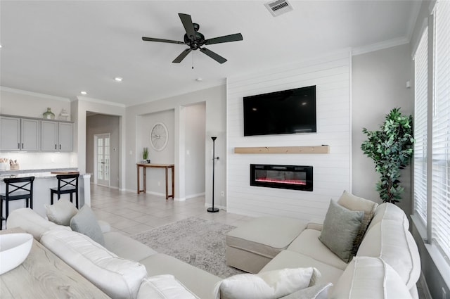 living room featuring light tile patterned floors, crown molding, a fireplace, and ceiling fan