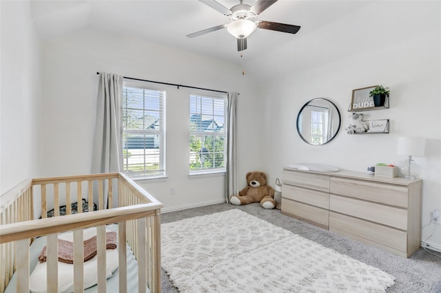 carpeted bedroom with vaulted ceiling, a nursery area, and ceiling fan