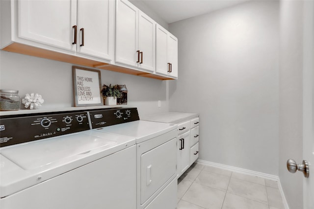 clothes washing area featuring cabinets, light tile patterned floors, and washing machine and clothes dryer