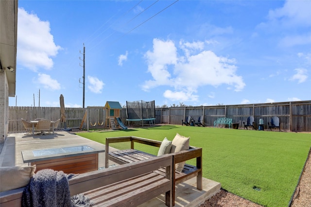 view of yard featuring a trampoline, a hot tub, a patio, and a playground