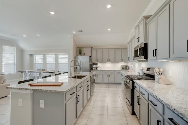 kitchen featuring a kitchen island with sink, light tile patterned floors, decorative backsplash, and stainless steel appliances