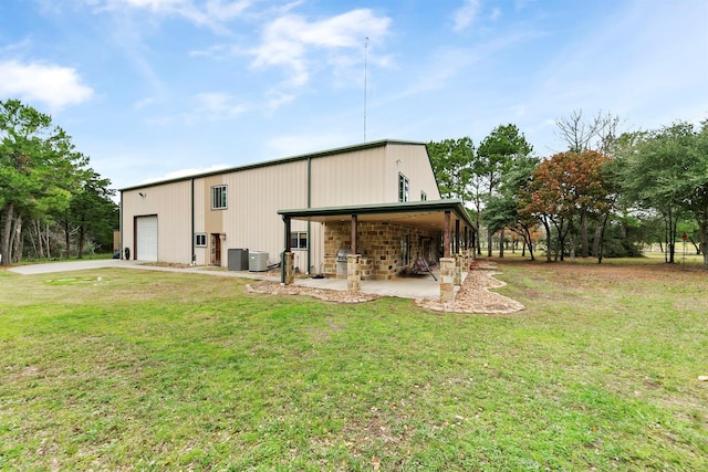 rear view of property featuring a garage, a yard, and central AC