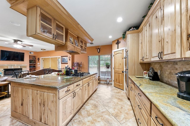 kitchen with appliances with stainless steel finishes, light brown cabinetry, backsplash, ceiling fan, and light stone counters