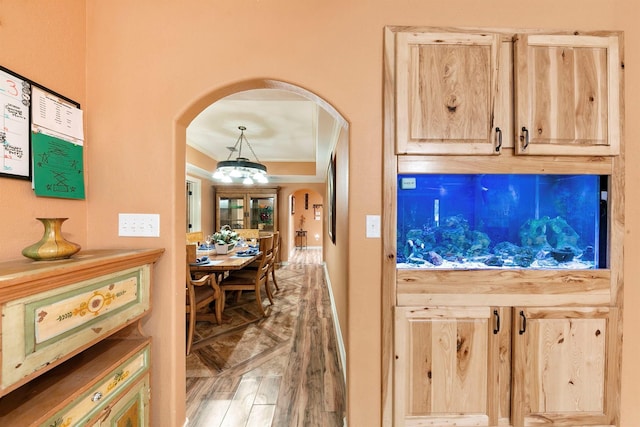 kitchen with pendant lighting, light brown cabinetry, ornamental molding, and hardwood / wood-style floors