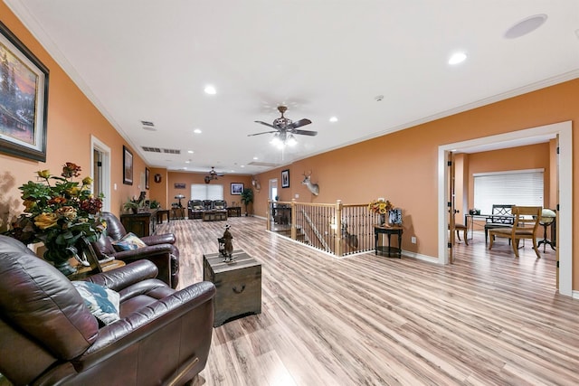 living room featuring ornamental molding, ceiling fan, and light wood-type flooring