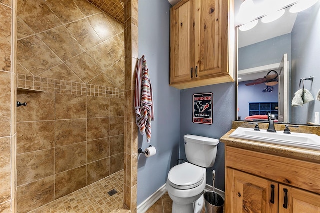 bathroom with a tile shower, vanity, tile patterned floors, and toilet