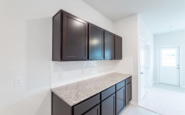 13301 Villa Sola Dr, La Marque, TX 77568 - kitchen with light stone counters, light tile patterned floors, dark brown cabinets, and backsplash