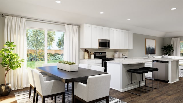 kitchen featuring stainless steel appliances, white cabinetry, a kitchen island, and a wealth of natural light