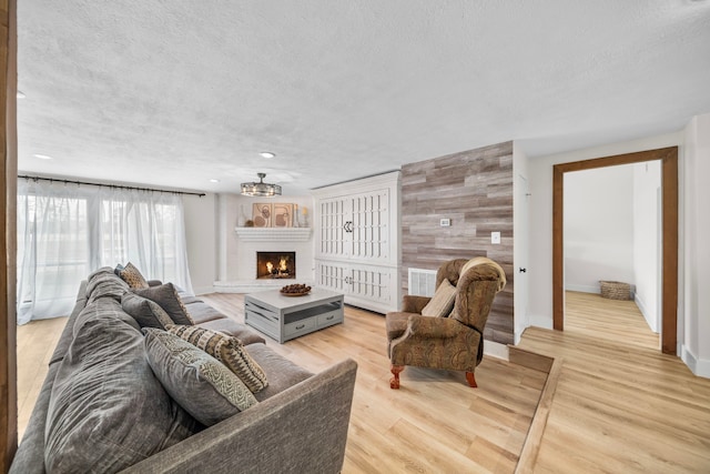 living room featuring light hardwood / wood-style floors, a textured ceiling, and wood walls