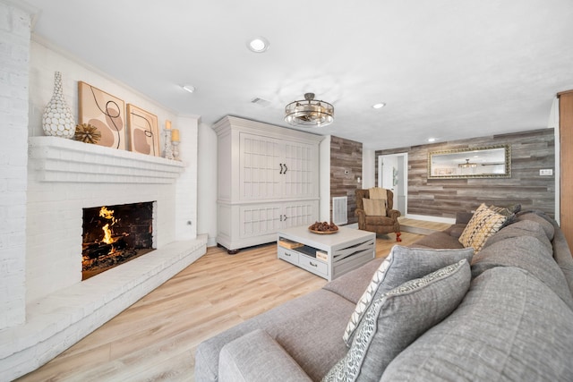 living room with a brick fireplace, wooden walls, and light wood-type flooring