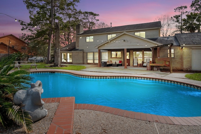 pool at dusk featuring an outdoor hangout area and a patio area