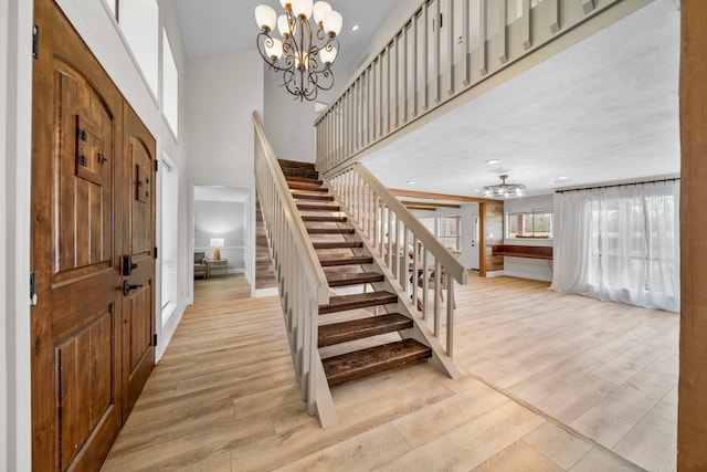 foyer featuring an inviting chandelier, light hardwood / wood-style flooring, and a high ceiling