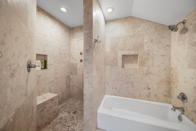 bathroom with vaulted ceiling and tiled shower / bath