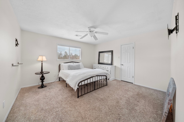 bedroom with ceiling fan, light carpet, and a textured ceiling