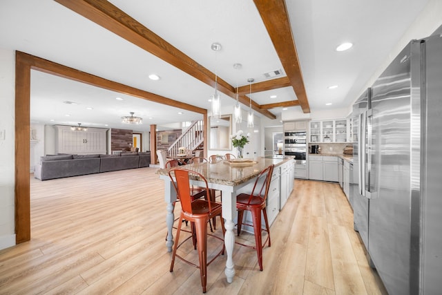 kitchen with a breakfast bar area, white cabinetry, decorative light fixtures, a center island, and stainless steel appliances