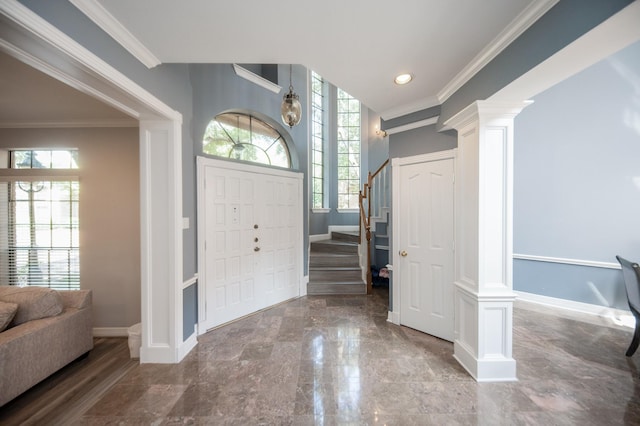 foyer entrance featuring crown molding and decorative columns