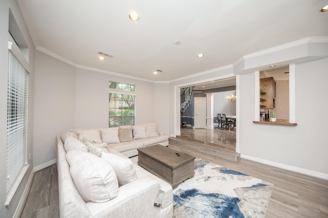 living room with an inviting chandelier, hardwood / wood-style floors, and crown molding