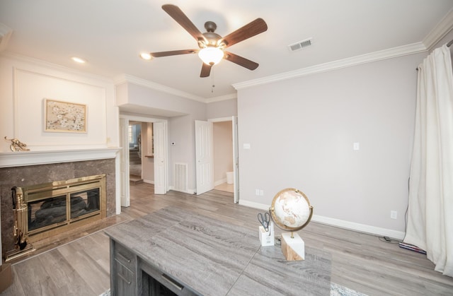 dining room featuring crown molding, ceiling fan, a high end fireplace, and light hardwood / wood-style flooring