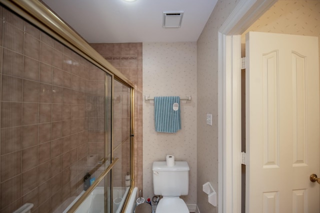 bathroom featuring bath / shower combo with glass door and toilet