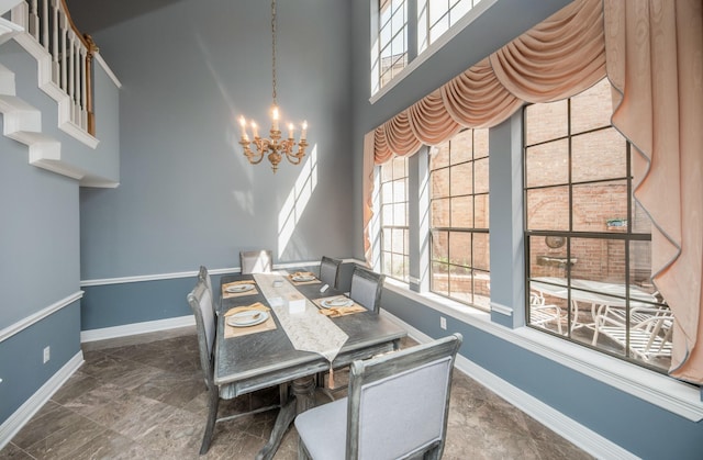 dining room featuring a notable chandelier, a towering ceiling, and a wealth of natural light