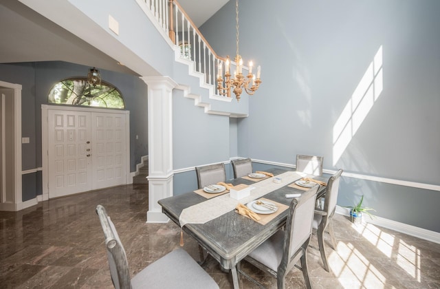 dining space featuring a notable chandelier, decorative columns, and a high ceiling