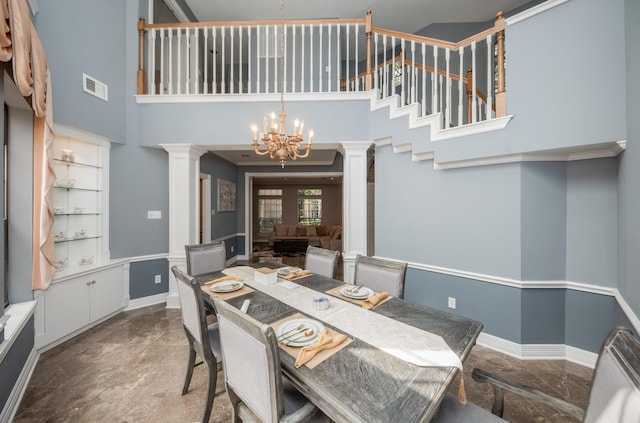 dining space with an inviting chandelier, a towering ceiling, and ornate columns