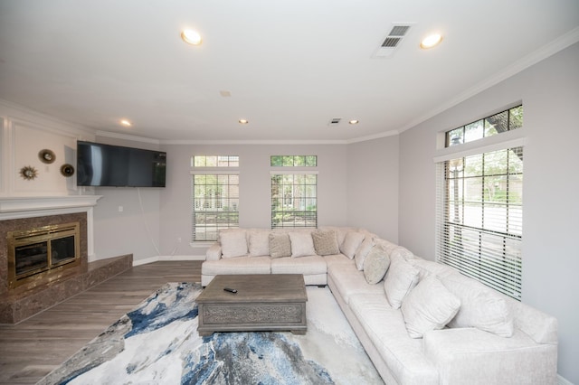 living room with crown molding, a premium fireplace, and hardwood / wood-style floors