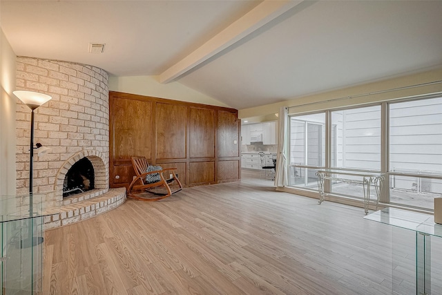 unfurnished living room with a fireplace, light hardwood / wood-style floors, and lofted ceiling with beams