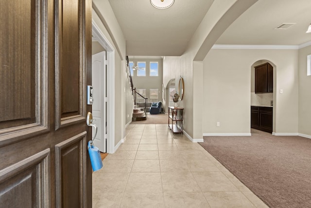 carpeted entryway featuring ornamental molding