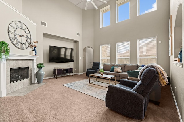 carpeted living room with a tiled fireplace and ceiling fan