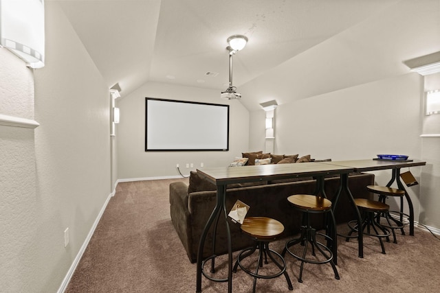 carpeted cinema room with lofted ceiling and bar